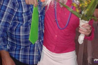 Un couple danse dans une salle faiblement éclairée avec des lumières colorées et une ambiance festive.