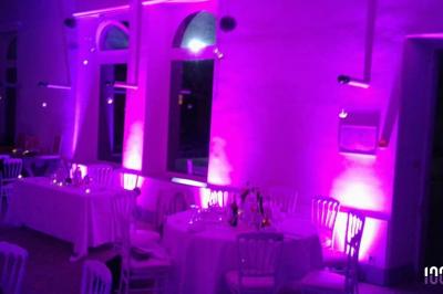 Un couple danse dans une salle faiblement éclairée avec des lumières colorées et une ambiance festive.