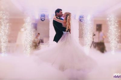 Un couple danse dans une salle faiblement éclairée avec des lumières colorées et une ambiance festive.