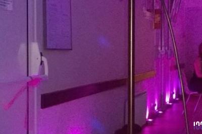 Un couple danse dans une salle faiblement éclairée avec des lumières colorées et une ambiance festive.