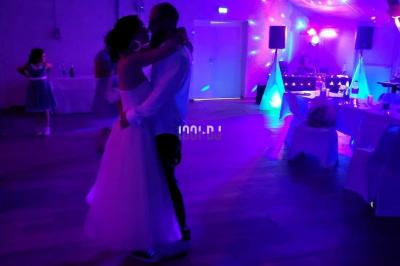 Un couple danse dans une salle faiblement éclairée avec des lumières colorées et une ambiance festive.