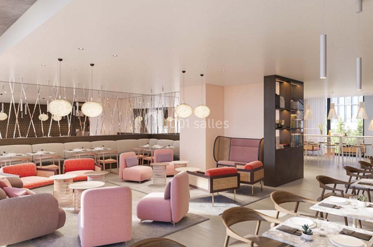 Salle lumineuse avec tables dressées, fauteuils roses et éclairage suspendu, décor moderne et épuré.