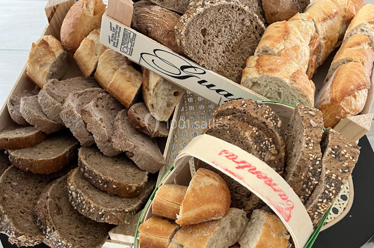 Assortiment de pains variés, incluant des baguettes, du pain complet et des tranches aux graines, disposés dans des paniers.