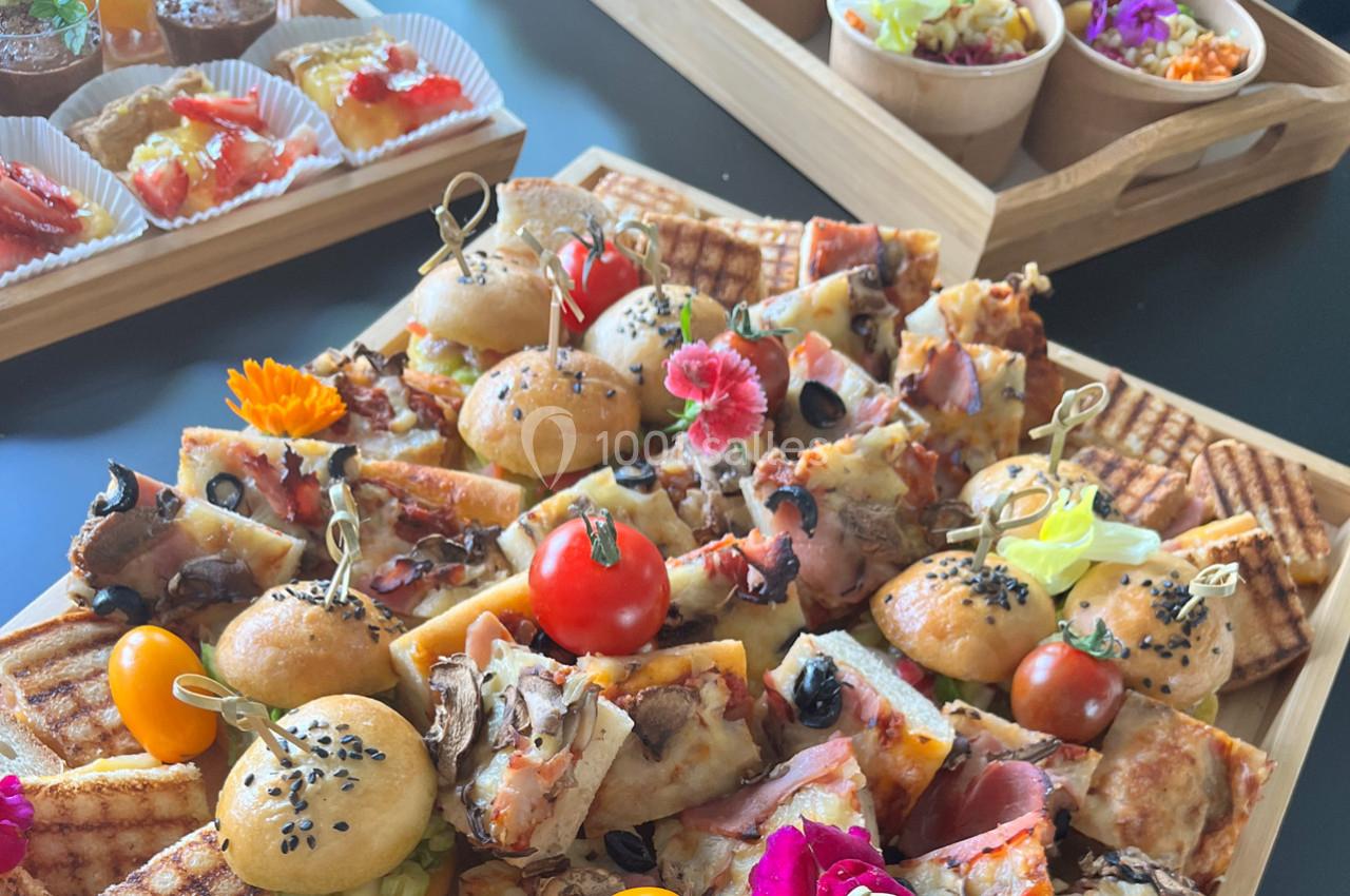 Plateau varié de bouchées salées et sucrées, incluant mini-sandwichs, pizzas, gaufres et desserts colorés.