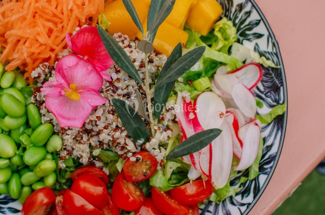 Salade colorée composée de quinoa, tomates cerises, radis, edamame, carottes râpées, mangue et fleurs comestibles.