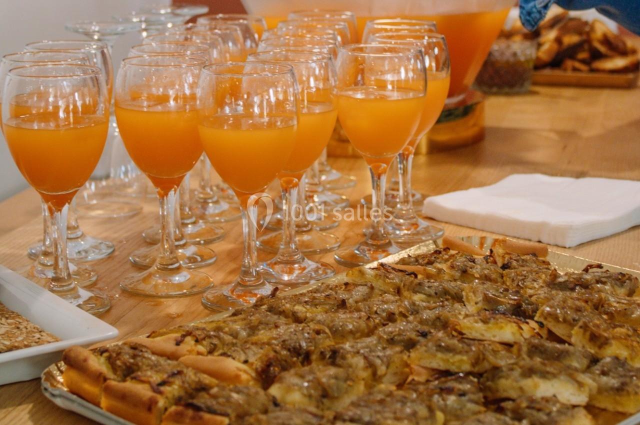 Plateau de tarte salée aux oignons devant des verres de jus orange disposés sur une table en bois.