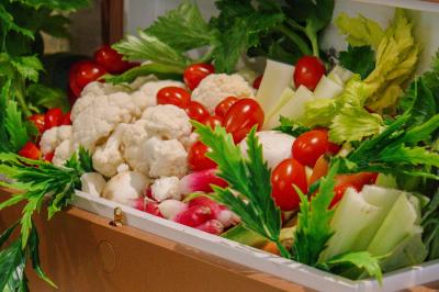 Plateau de légumes frais comprenant chou-fleur, tomates cerises, céleri, radis et feuilles vertes.