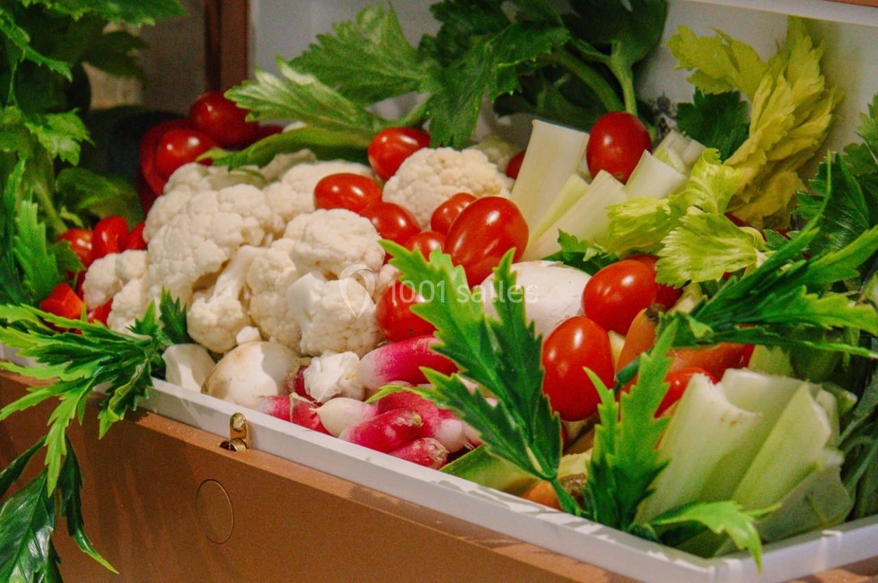 Plateau de légumes frais comprenant chou-fleur, tomates cerises, céleri, radis et feuilles vertes.