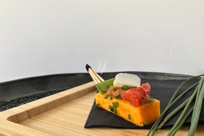 Bouchée de polenta garnie de tomate confite, fromage et ciboulette, présentée sur un plateau en bois avec décoration…