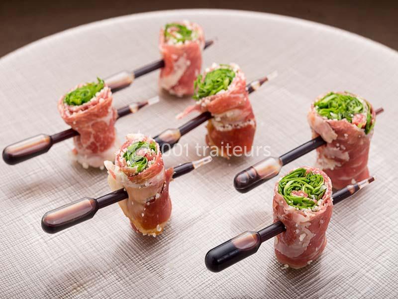 Roulés de jambon cru garnis de légumes verts, présentés sur des pipettes de sauce sur une assiette claire.