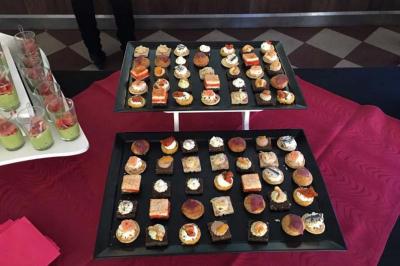 Plateaux de canapés variés disposés sur une nappe rouge, accompagnés de verrines en arrière-plan.