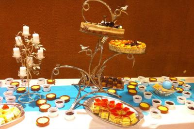 Table de buffet avec des desserts variés, dont des gâteaux, tartelettes et verrines, présentés sur des supports décoratifs.