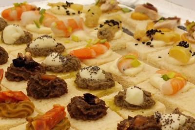Plateau de canapés variés avec garnitures comme crevettes, tapenade, fromage et légumes sur pain blanc.