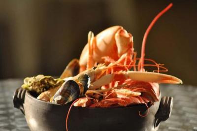 Assortiment de fruits de mer dans un plat en céramique, comprenant crevettes, coquillages et crustacés.