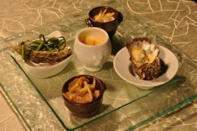 Assortiment de plats gastronomiques comprenant fruits de mer, légumes et une petite soupe sur une table élégante.