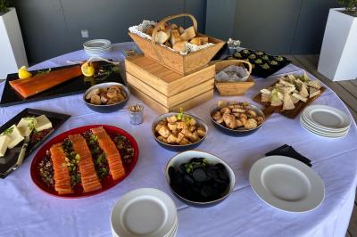 Buffet avec saumon fumé, fromages, pains, verrines et divers amuse-bouches disposés sur une table blanche.