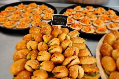 Plateau de mini-burgers au poulet et assiettes de canapés garnis, présentés sur une table de buffet.