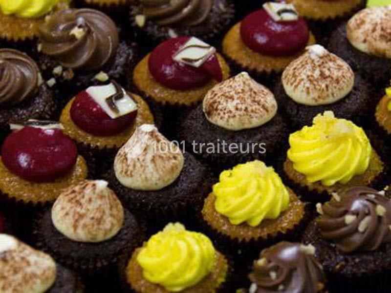 Assortiment de petits cupcakes décorés de glaçages colorés et variés disposés en rangées serrées.