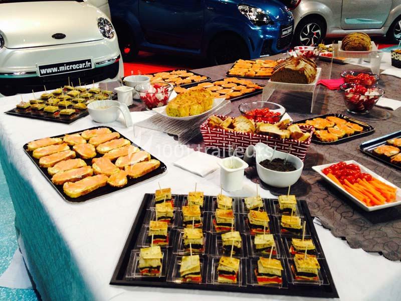 Buffet composé de canapés, verrines, pains et amuse-bouches variés, disposé sur une table blanche.