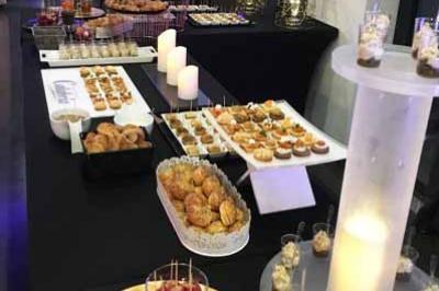 Buffet de desserts variés avec verrines, pâtisseries et bougies décoratives dans une salle de réception élégante.