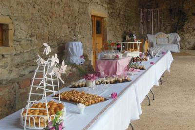 Table de buffet décorée avec des fleurs roses, disposée dans une salle en pierre avec des desserts et des amuse-bouches.
