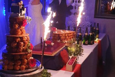 Table de desserts de mariage avec pièce montée, fontaine de champagne et décorations lumineuses.