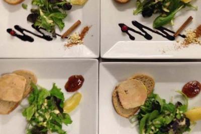Assiettes dressées avec foie gras sur pain, salade verte, condiments, sauce balsamique et décorations culinaires.