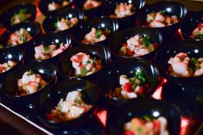 Petits bols noirs contenant des portions de ceviche coloré avec des morceaux de poisson, légumes et herbes fraîches.