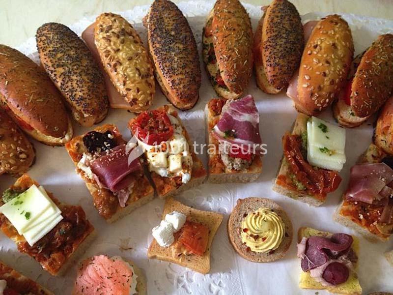 Assortiment de petits pains garnis et canapés variés disposés sur un plateau.