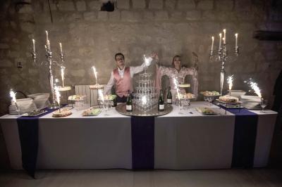 Un couple debout derrière une table décorée avec une fontaine à champagne, des bougies et des desserts.