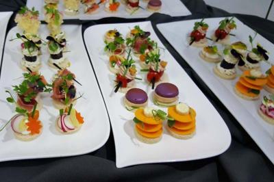 Plateaux de canapés variés et colorés présentés sur des assiettes blanches, disposés sur une nappe sombre.