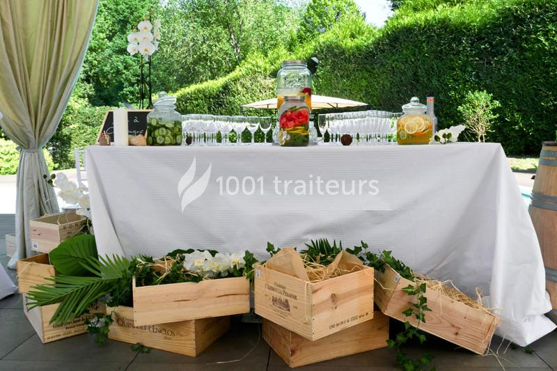 Table décorée pour un buffet en extérieur avec boissons infusées, verres alignés et caisses en bois ornées de feuillage.