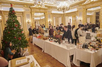 Marché de Noël dans une salle élégante avec des stands de produits artisanaux et un sapin décoré.
