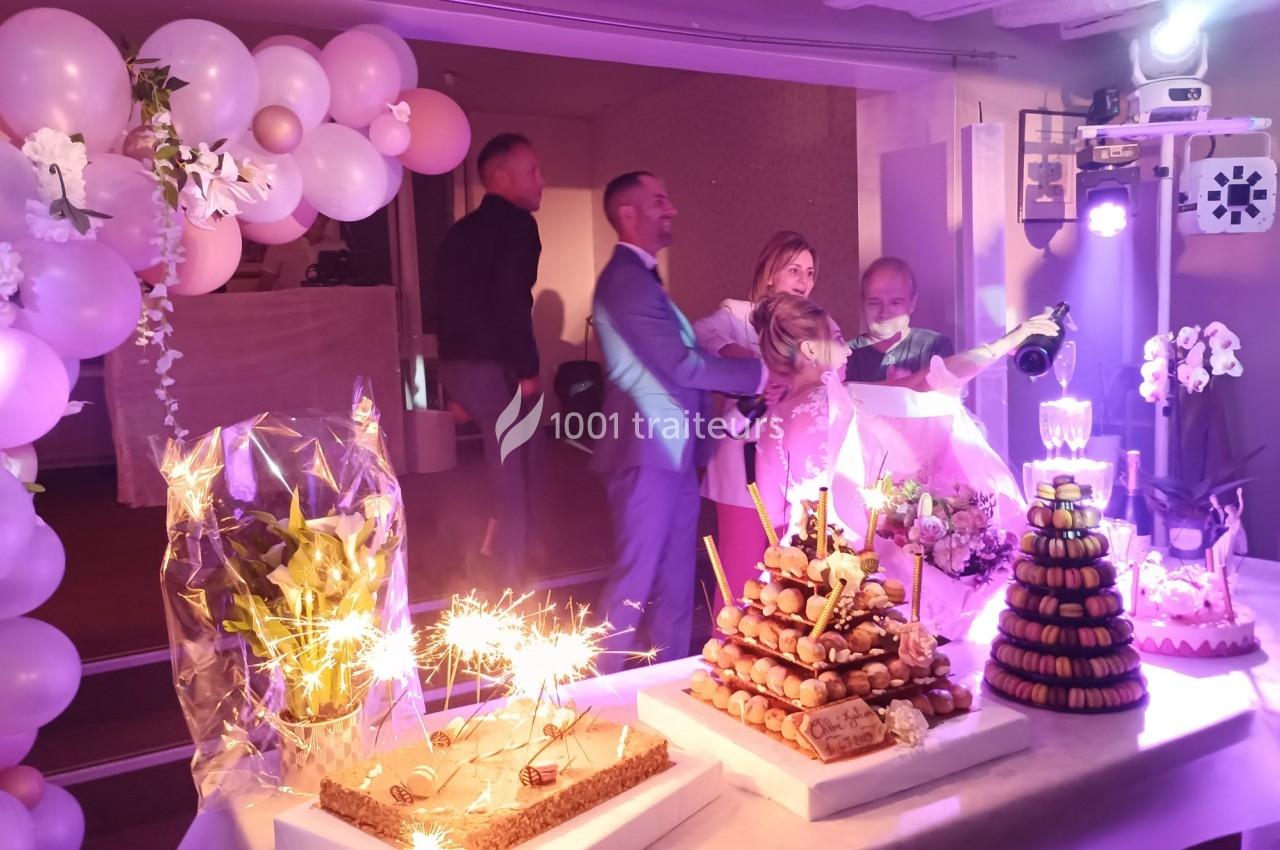 Table décorée avec des desserts festifs, dont une pièce montée et des gâteaux, entourée de ballons et éclairée par des…