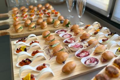 Plateaux de mini-sandwichs, verrines et amuse-bouches variés disposés sur une table dans un cadre lumineux.