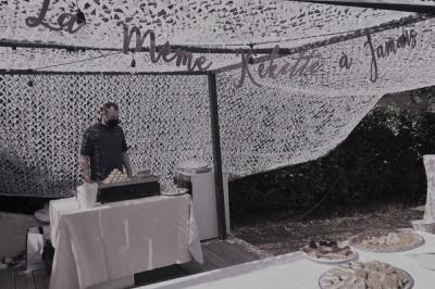 Stand de restauration en extérieur avec des tables garnies de plats variés sous un filet d'ombrage.