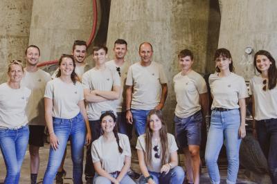 Un groupe de personnes posant devant de grandes cuves en béton dans un environnement industriel.