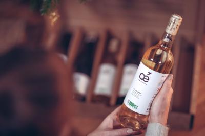 Une personne tient une bouteille de vin blanc biologique devant une caisse contenant d'autres bouteilles.