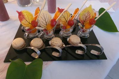 Plateau de verrines décorées de feuilles colorées, accompagné de macarons, présenté sur une table blanche.