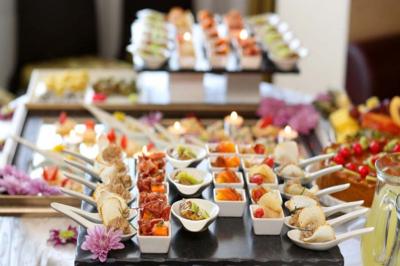 Plateau de verrines et amuse-bouches variés disposés sur une table décorée de fleurs.