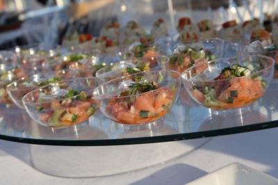 Coupes transparentes contenant des portions de tartare de saumon avec herbes fraîches, présentées sur un plateau en verre.
