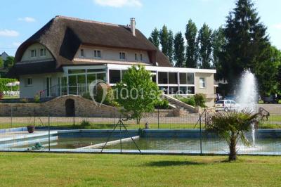 Salle décorée pour un événement avec tables dressées, chandeliers, nappes blanches et buffet garni en arrière-plan.