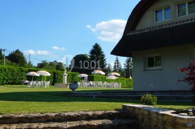 Salle décorée pour un événement avec tables dressées, chandeliers, nappes blanches et buffet garni en arrière-plan.