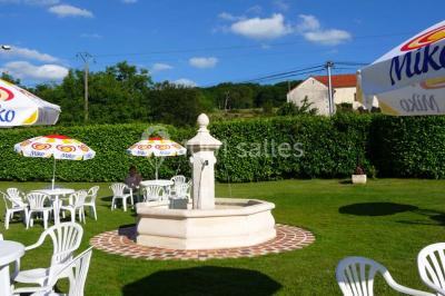 Salle décorée pour un événement avec tables dressées, chandeliers, nappes blanches et buffet garni en arrière-plan.