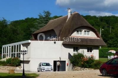 Salle décorée pour un événement avec tables dressées, chandeliers, nappes blanches et buffet garni en arrière-plan.