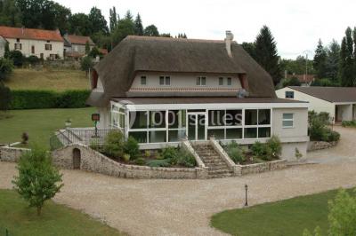 Salle décorée pour un événement avec tables dressées, chandeliers, nappes blanches et buffet garni en arrière-plan.