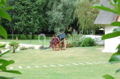 Salle décorée pour un événement avec tables dressées, chandeliers, nappes blanches et buffet garni en arrière-plan.