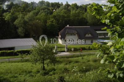 Salle décorée pour un événement avec tables dressées, chandeliers, nappes blanches et buffet garni en arrière-plan.