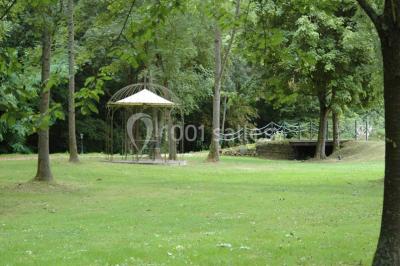 Salle décorée pour un événement avec tables dressées, chandeliers, nappes blanches et buffet garni en arrière-plan.