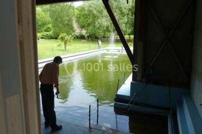 Salle décorée pour un événement avec tables dressées, chandeliers, nappes blanches et buffet garni en arrière-plan.